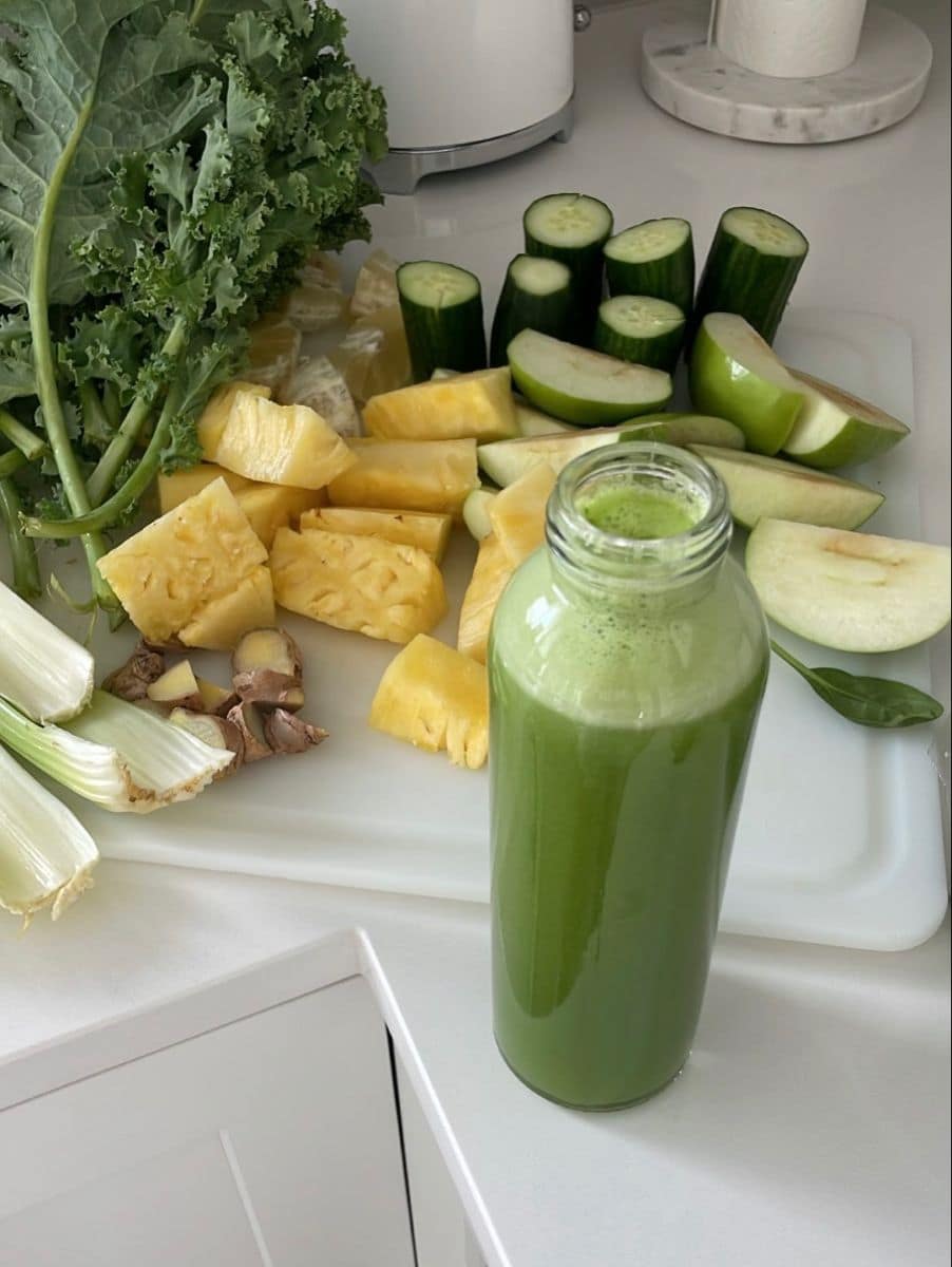 Fresh produce and a green smoothie laid out on a kitchen counter
